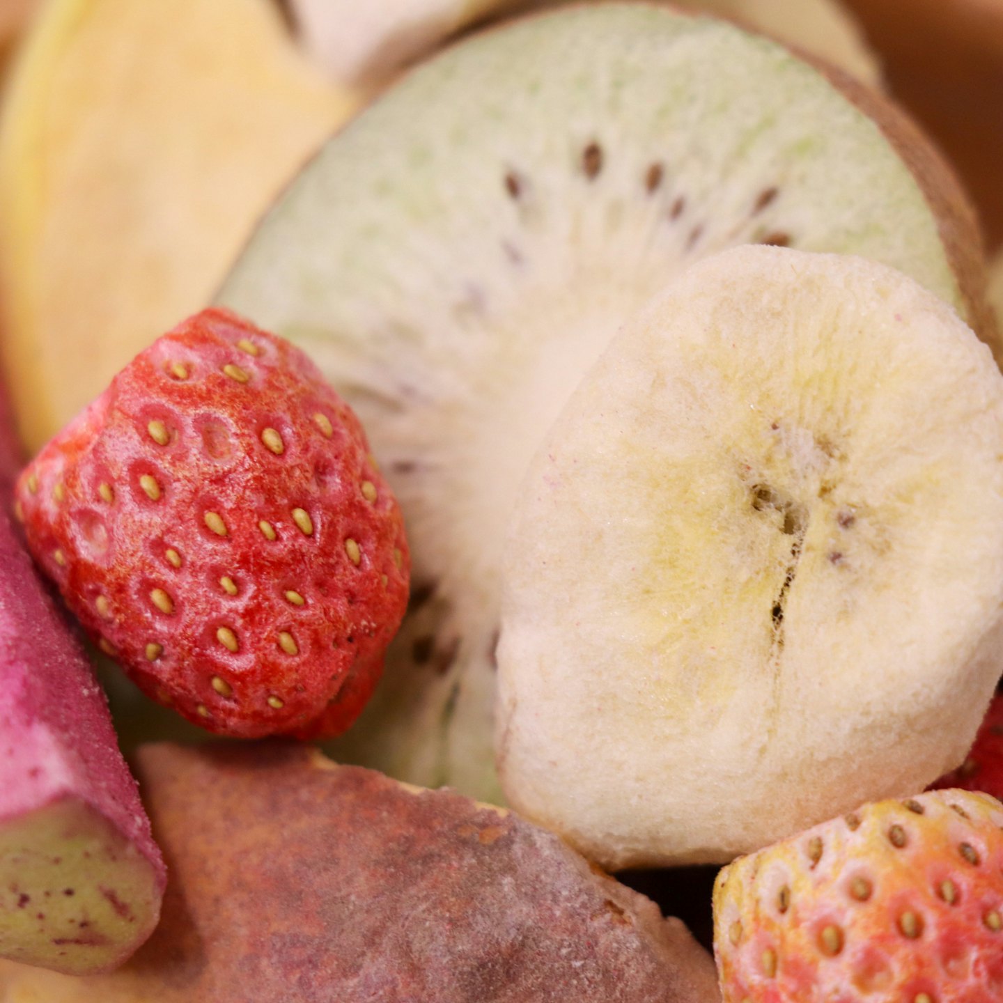 Suszone plasterki truskawek, kiwi i banana ułożone na stole.